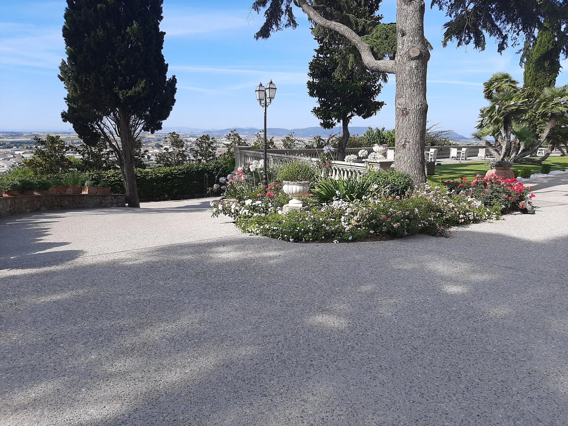 Il piazzale della villa con l'aiuola fiorita, i lampioni e la vista sulla costa